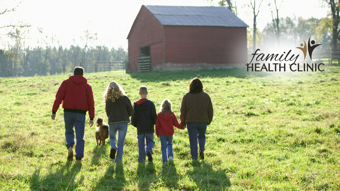 farming family walking in a field towards a red barn